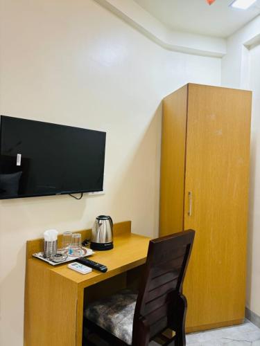 a desk with a television and a chair in a room at Hotel Fun Suite- Baner Hill in Pune