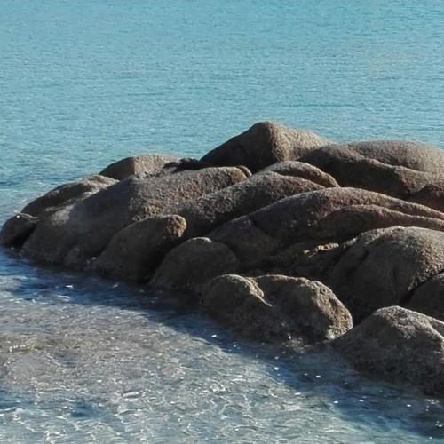 a group of rocks in the water on a beach at Villa Antonella in Villasimius
