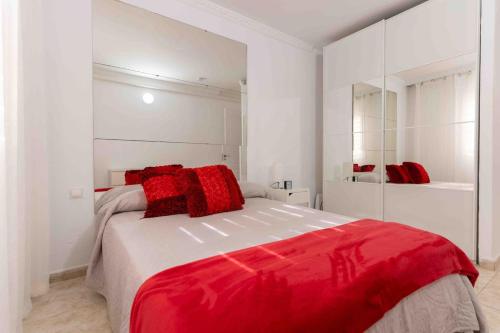a white bedroom with a red blanket on a bed at Beproud Gc in Maspalomas
