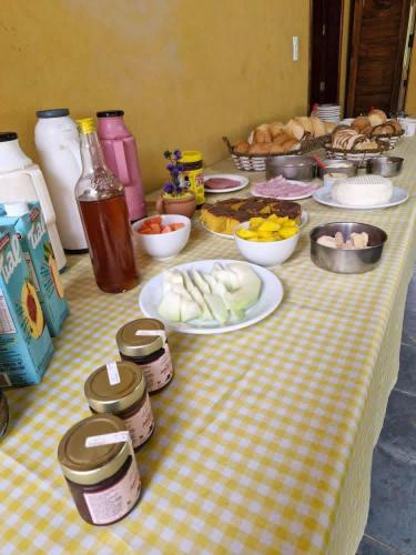 een tafel met borden met voedsel op een tafel bij Pousada Fazenda e Pesqueiro Chalé da serra in Conceição da Ibitipoca