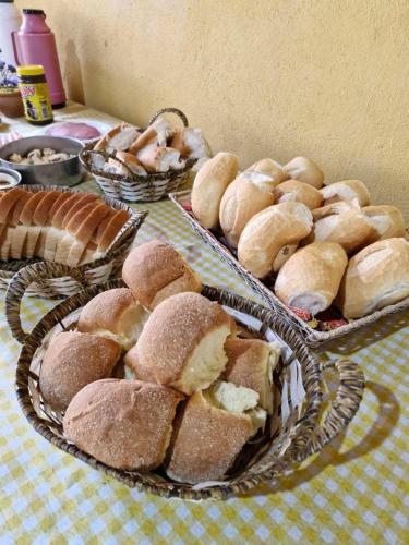 een tafel met manden brood en gebak bij Pousada Fazenda e Pesqueiro Chalé da serra in Conceição da Ibitipoca