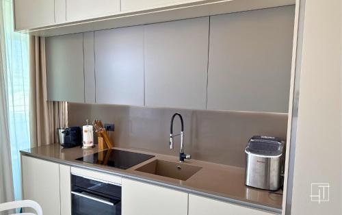 a kitchen with white cabinets and a sink at HT - Luxury apartment at Palm Beach Jesolo in Lido di Jesolo