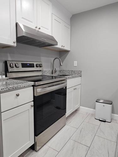 a kitchen with a black stove and white cabinets at Cozy Norment Forest Apartment in Lumberton