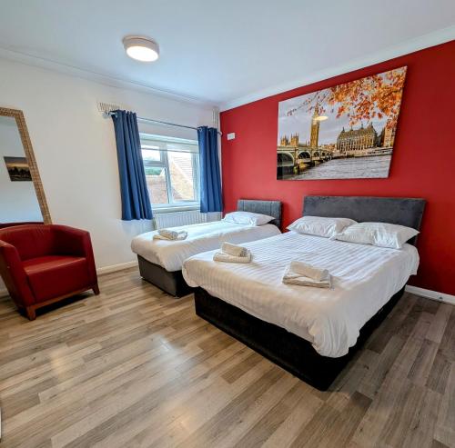 Dos camas en una habitación con una pared roja. en OYO Aparthotel Hathern - Loughborough, en Hathern