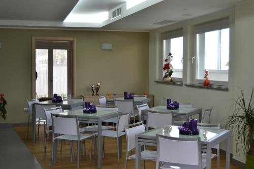 un comedor con mesas, sillas blancas y ventanas en 7venti, en Francavilla al Mare