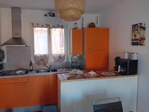 une cuisine avec des armoires orange et un comptoir dans l'établissement Villa de luxe en bord de mer Résidence Torra Mare a Prunete, à Cervione