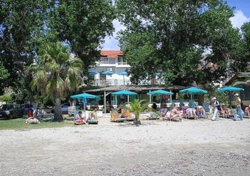 a group of people sitting under blue umbrellas on a beach at Hercules Sea Front Studios in Katelios