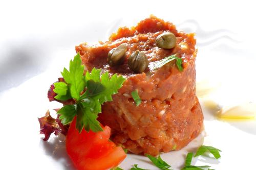 a piece of food on a plate with a tomato at Park Hotel Pruhonice in Pruhonice
