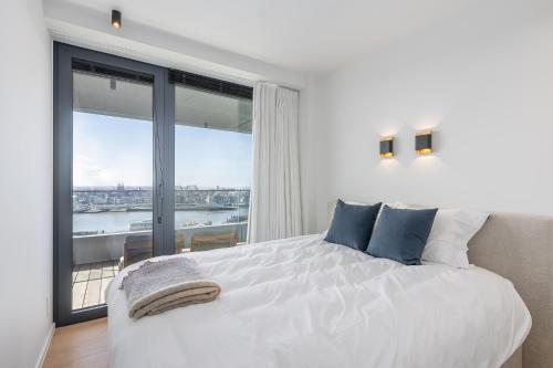 una camera da letto con un letto bianco e una grande finestra di Sea meets sky - Ensor a Ostenda