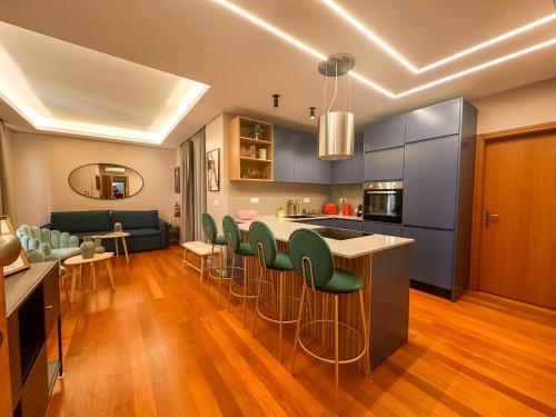 a kitchen with a bar with green chairs and a couch at Suites Do Carmo in Funchal