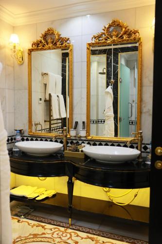 a bathroom with two sinks and two mirrors at Golden Palace Hotel Yerevan in Yerevan