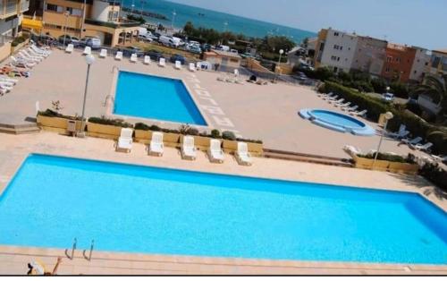 une vue d'une piscine dans un complexe hôtelier dans l'établissement Studio chic climatisé avec vue mer et piscine à 100m plage du Môle, au Cap d'Agde