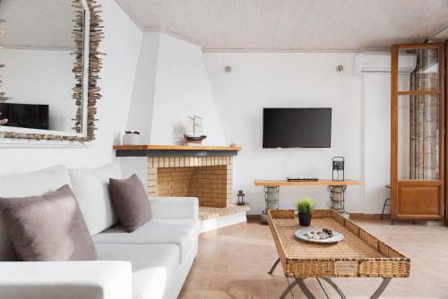 a living room with a white couch and a fireplace at Aura Seafront Villa in Neon Oitilon