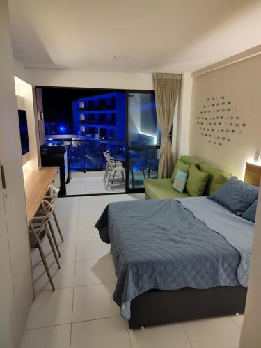 a bedroom with a bed and a view of a balcony at Malia Beach Muro Alto 300 Metros Do Mar in Porto De Galinhas