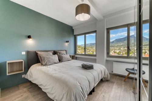 Cet appartement comprend une chambre dotée d'un grand lit, de murs bleus et de fenêtres. dans l'établissement Appartement avec vue panoramique sur le Lac du Bourget, à Aix-les-Bains
