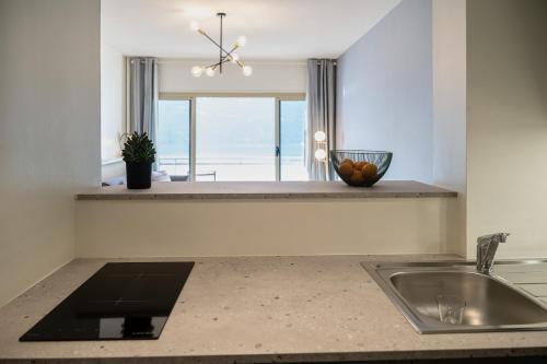un comptoir de cuisine avec un évier et une fenêtre dans l'établissement Appartement avec vue panoramique sur le Lac du Bourget, à Aix-les-Bains