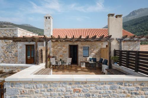 a stone house with a patio with a table and chairs at Aura Seafront Villa in Neon Oitilon
