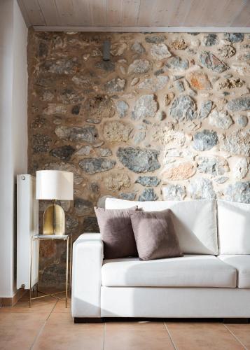 a living room with a white couch in front of a stone wall at Aura Seafront Villa in Neon Oitilon