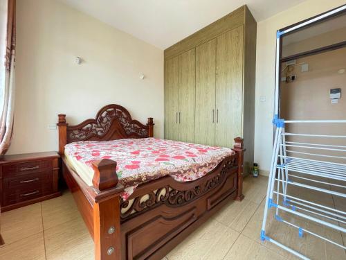 a bedroom with a bed and a wooden cabinet at Lux Suites Thika Gateway Apartments in Thika