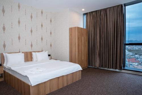 een hotelkamer met een bed en een groot raam bij Royal Bakrajo Hotel in As Sulaymānīyah