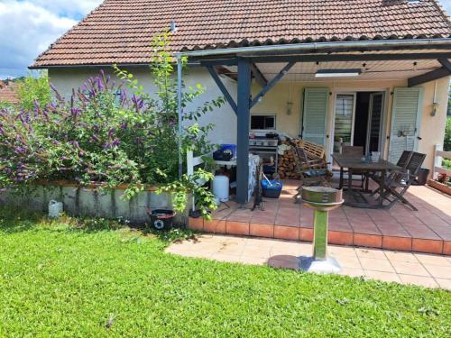 a house with a patio with a table and a grill at Maison in Naucelles