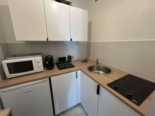une petite cuisine avec un micro-ondes et un évier dans l'établissement Appartement T2 avec Jardin, à 200m de la Plage - 6 Couchages, Saint-Hilaire-de-Riez - FR-1-224C-314, à Saint-Hilaire-de-Riez