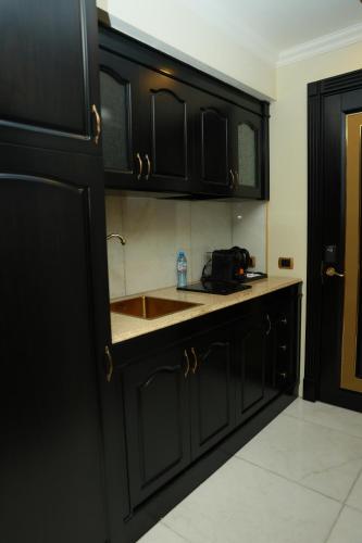 a kitchen with black cabinets and a sink at Golden Palace Hotel Yerevan in Yerevan