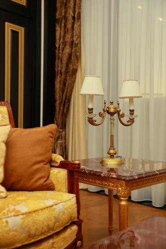 a living room with a table with two lamps and a chair at Golden Palace Hotel Yerevan in Yerevan