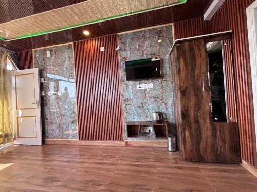 a room with a stone wall and a wooden floor at Noorani Hills Home Stay 2 BHK in Patta