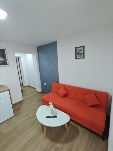a living room with a red couch and a table at Белчини in Dobrinishte