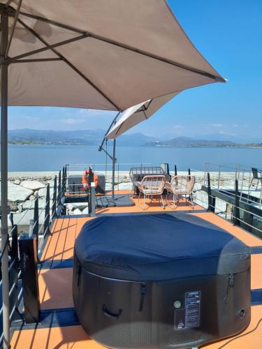 an umbrella on a deck with a table and chairs at Floating Experience Black Pearl, Lago Maggiore in Dormelletto