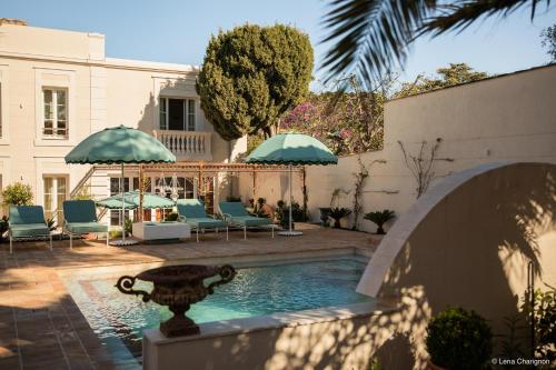 - une piscine avec des chaises et des parasols dans une cour dans l'établissement Villa Pâquerette, Marseille, à Marseille