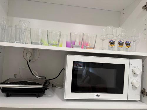 a microwave on a shelf with glasses on it at Cvetkovic apartman in Soko Banja