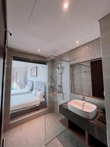 a bathroom with a bed and a sink and a mirror at Apec Mandala Mũi Né Sun Sea Condotel in Mui Ne
