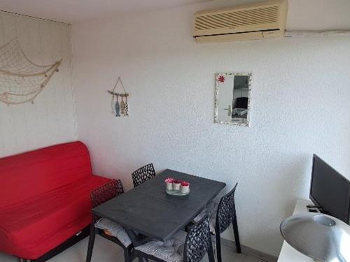 un salon avec une table et un canapé rouge dans l'établissement Studio cabine climatisé, piscine, parking, animaux admis, 350m plage - FR-1-250-62, au Grau-du-Roi
