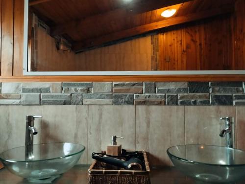 a bathroom with two glass sinks and a stone wall at Amplia casa y acogedora con jacuzzi in Puerto Montt