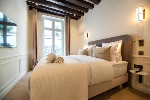 une chambre avec un grand lit blanc avec une fenêtre dans l'établissement Luxury one bedroom flat near Le Louvre I, à Paris