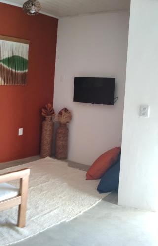 a bedroom with a flat screen tv on a wall at Recanto Manoah, TERRA in Caraíva