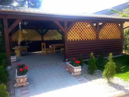 a wooden pavilion with a picnic table and flowers at Trend Hotel in Námestovo