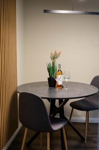 a table with a bottle of wine and two chairs at Little Bucharest downtown apartments Romana in Bucharest