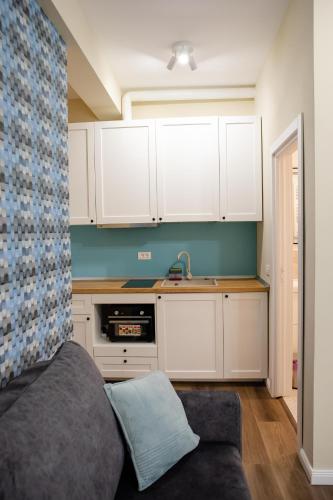 a kitchen with white cabinets and a couch in a room at Little Bucharest downtown apartments Romana in Bucharest