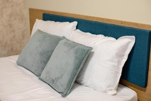 a bed with white pillows and a blue headboard at Little Bucharest downtown apartments Romana in Bucharest