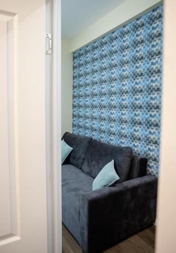 a couch in a living room with a blue wall at Little Bucharest downtown apartments Romana in Bucharest