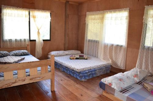 1 dormitorio con 2 camas y 2 ventanas en Batad View Inn and Restaurant, en Banaue