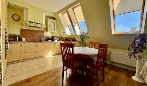 a kitchen with a table and chairs and windows at Apartament Pers - przytulny, klimatyzowany, z kominkiem i bezpłatnym parkingiem in Szczawno-Zdrój