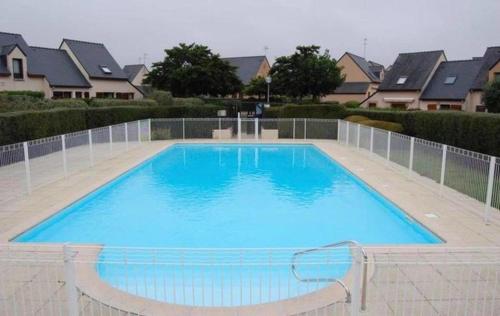 une grande piscine bleue en face de certaines maisons dans l'établissement Maisonnette 6 pers- Piscine commune - Plage à 500 m- LOEIZ, à Guidel-Plage