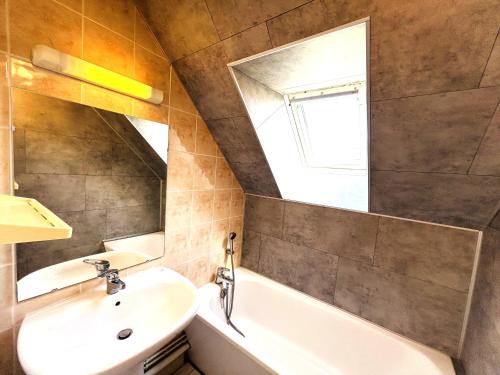 une salle de bain avec un lavabo, une baignoire et un miroir dans l'établissement Maisonnette 6 pers- Piscine commune - Plage à 500 m- LOEIZ, à Guidel-Plage