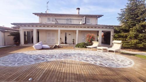 a house with chairs and a rug in front of it at Villa Concetta in Torre del Lago Puccini