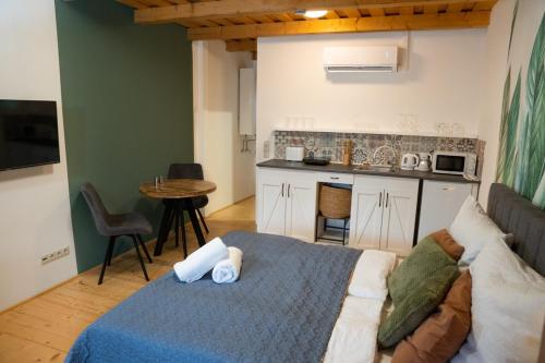 a bedroom with a bed and a kitchen with a table at Kapcsolj ki Wellness Apartmanház Demjén in Demjén