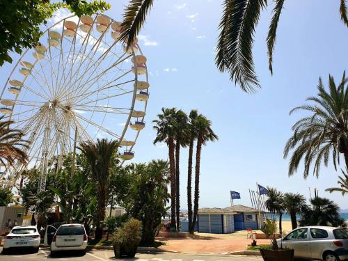 une roue ferris dans un parking avec des palmiers dans l'établissement Studio au Lavandou, Terrasse, Climatisation, Proche Plage - FR-1-251-857, au Lavandou